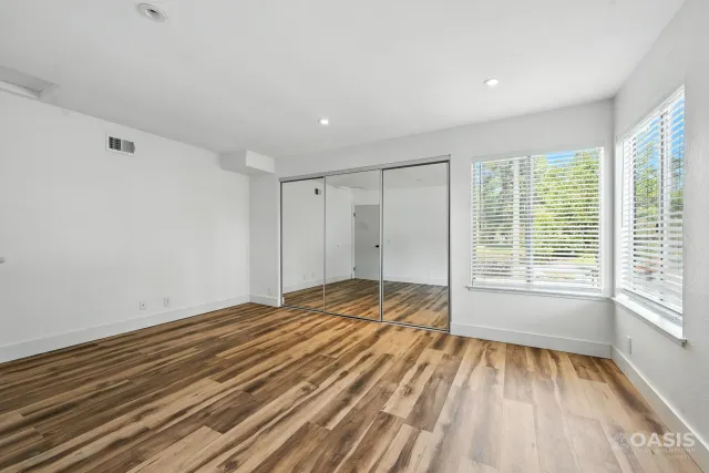 Finished bedroom with new flooring and mirrored closet doors