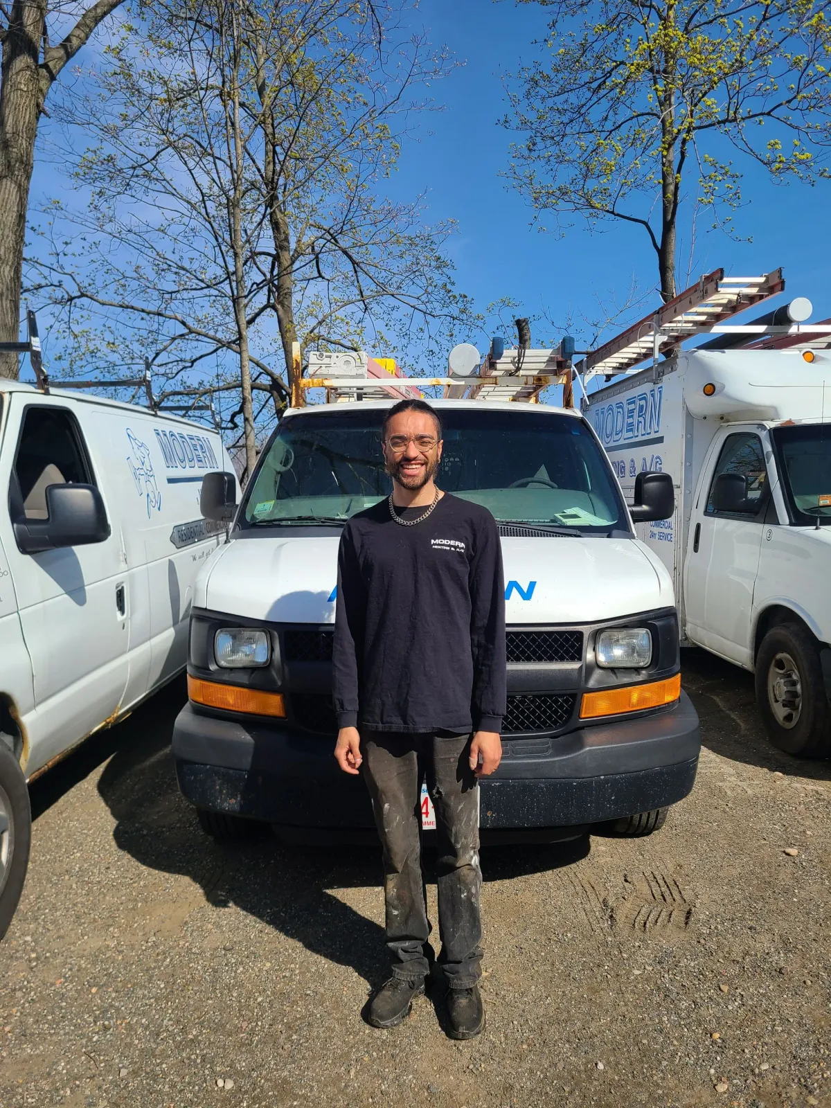 Person standing in front of a white utility van with blue lettering on a sunny day