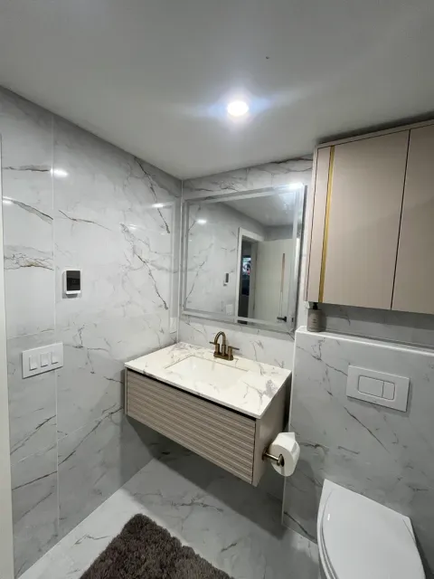 Wall-hung vanity with quartz top, brass faucet, and backlit mirror