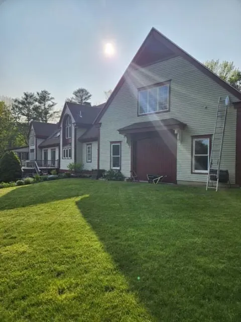 Sunlit suburban house with green lawn and a small front porch