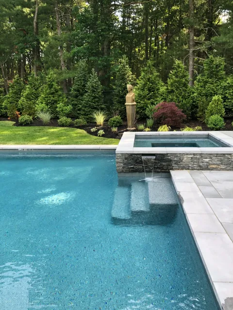 A North Andover pool design and build  complete with built-in spa and adjacent gardens provided a complete back yard transformation for ultimate function and beauty.