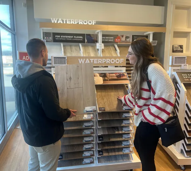 Women holding flooring sample in floor store