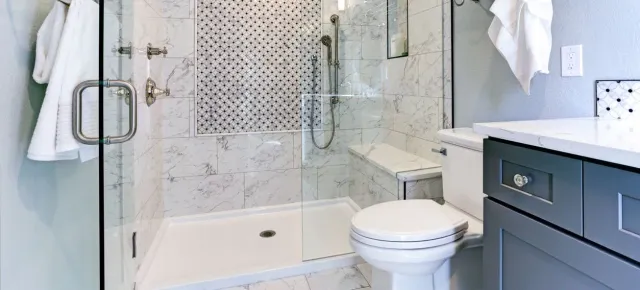 A bathroom with a toilet , sink , shower and glass door.