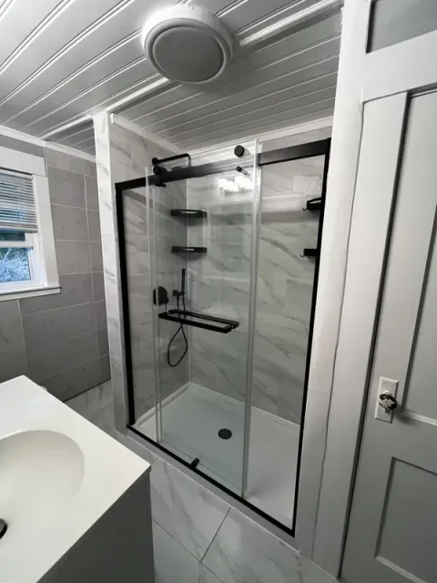 Finished tub-to-shower conversion with sliding glass door and matte black frame