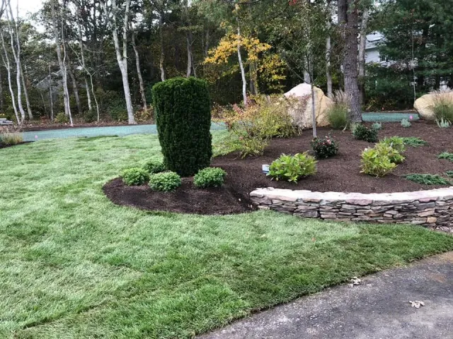 Low natural stone retaining wall integrated into a landscaped lawn