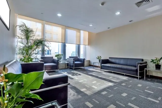 Clean office lobby with black seating, potted plants, and large windows with city views