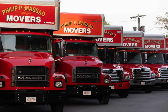 A row of red and white moving trucks parked in a parking lot.
