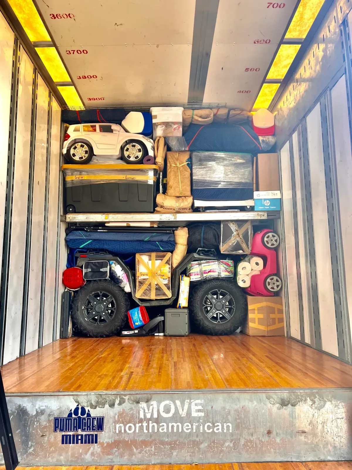 Moving truck packed with furniture, boxes, and a motorcycle, viewed from the open cargo bay.