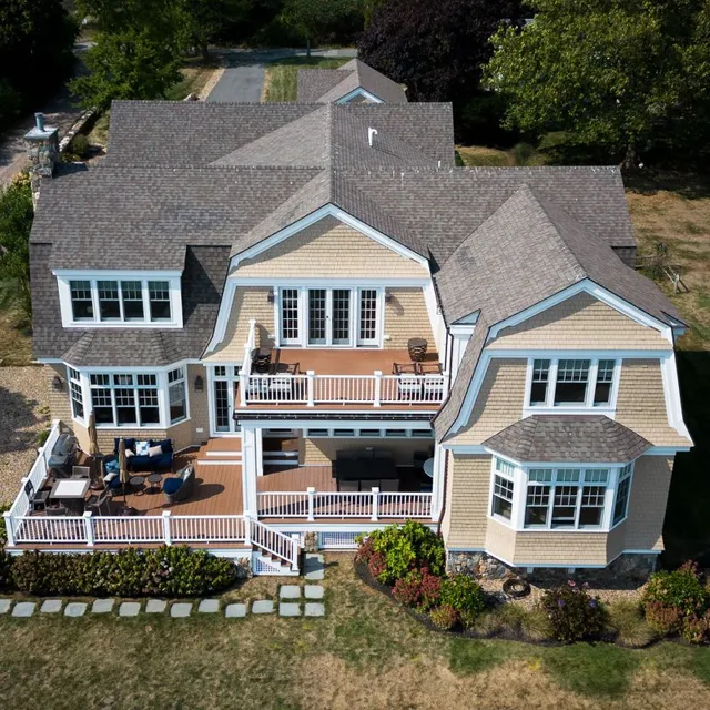 Aerial view of a home with beige exterior and white trim and fencing and large deck