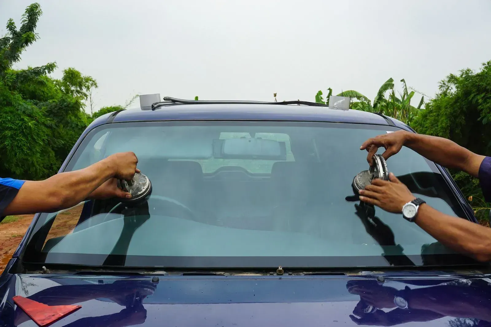 Auto glass technicians setting a windshield with suction-cup tools
