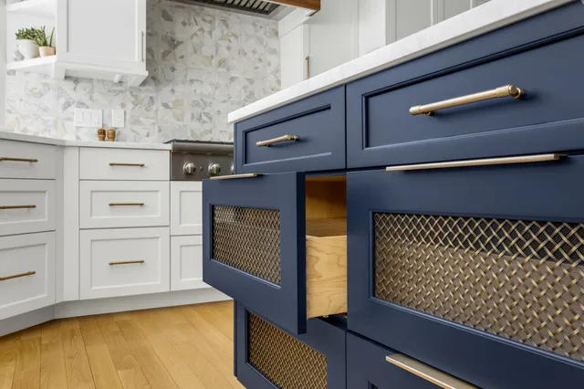 Navy blue kitchen cabinets with gold hardware and wire mesh inset panels
