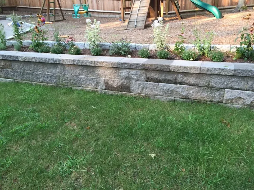 A backyard with a brick wall and a playground in the background.