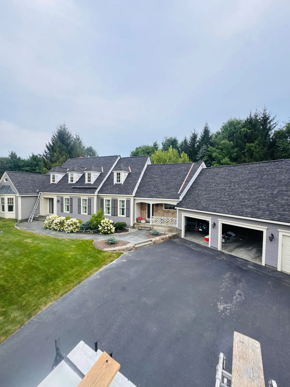 Suburban house with gray roof, attached garage, asphalt driveway, and landscaped front yard