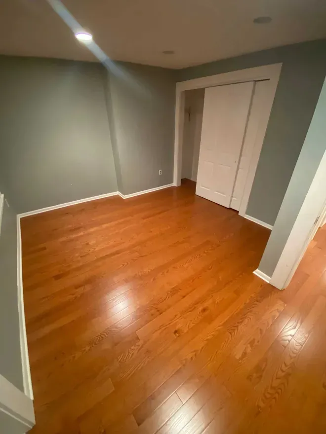 Room with hardwood floor, gray walls, and white trim, door.