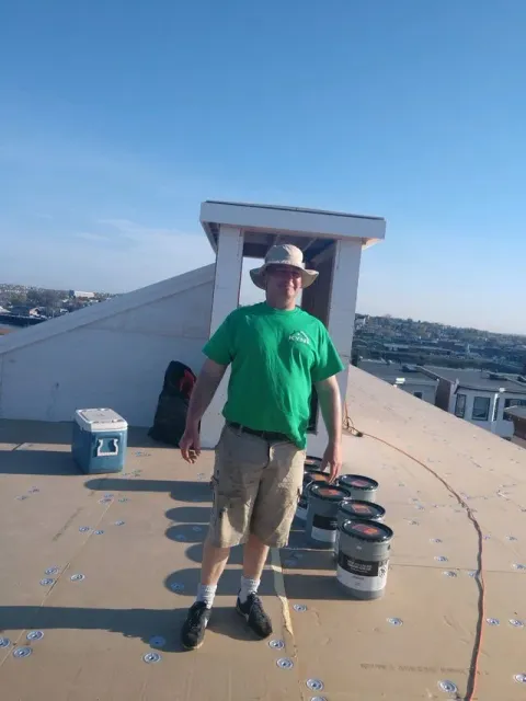 man standing on roof with cans