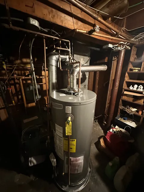 Traditional gas tank water heater swap — new copper flex connectors, sediment trap on the gas line, and a proper draft hood for safe combustion venting.