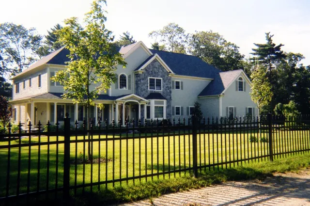 Black ornamental aluminum fence in front of a home