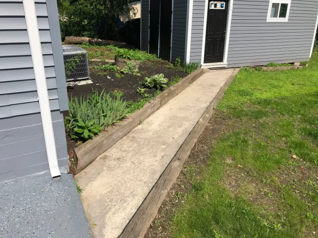 Side of a house with gray siding and a garden