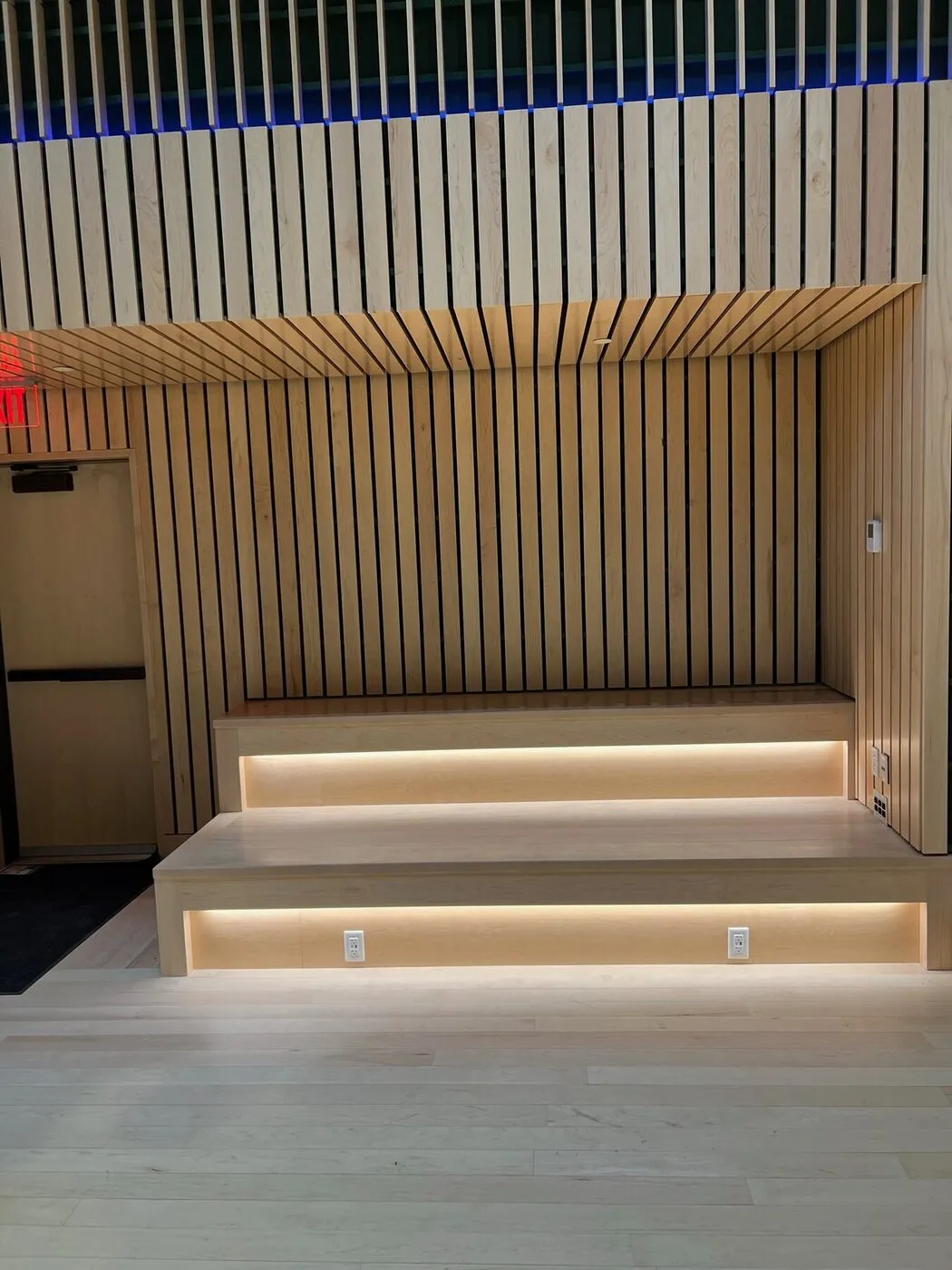 Slatted wood accent wall with integrated LED lighting and a floating step