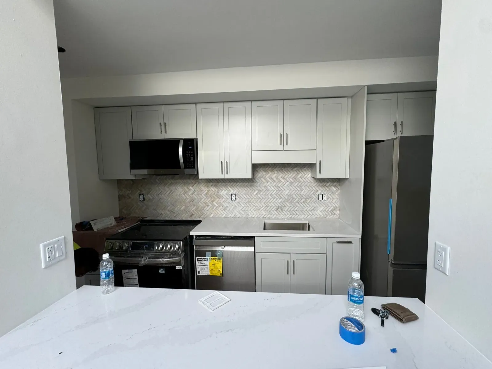 Newly renovated kitchen with gray cabinets, appliances, and backsplash.