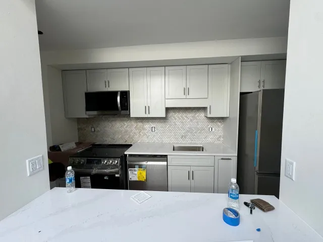 Newly renovated kitchen with gray cabinets, appliances, and backsplash.