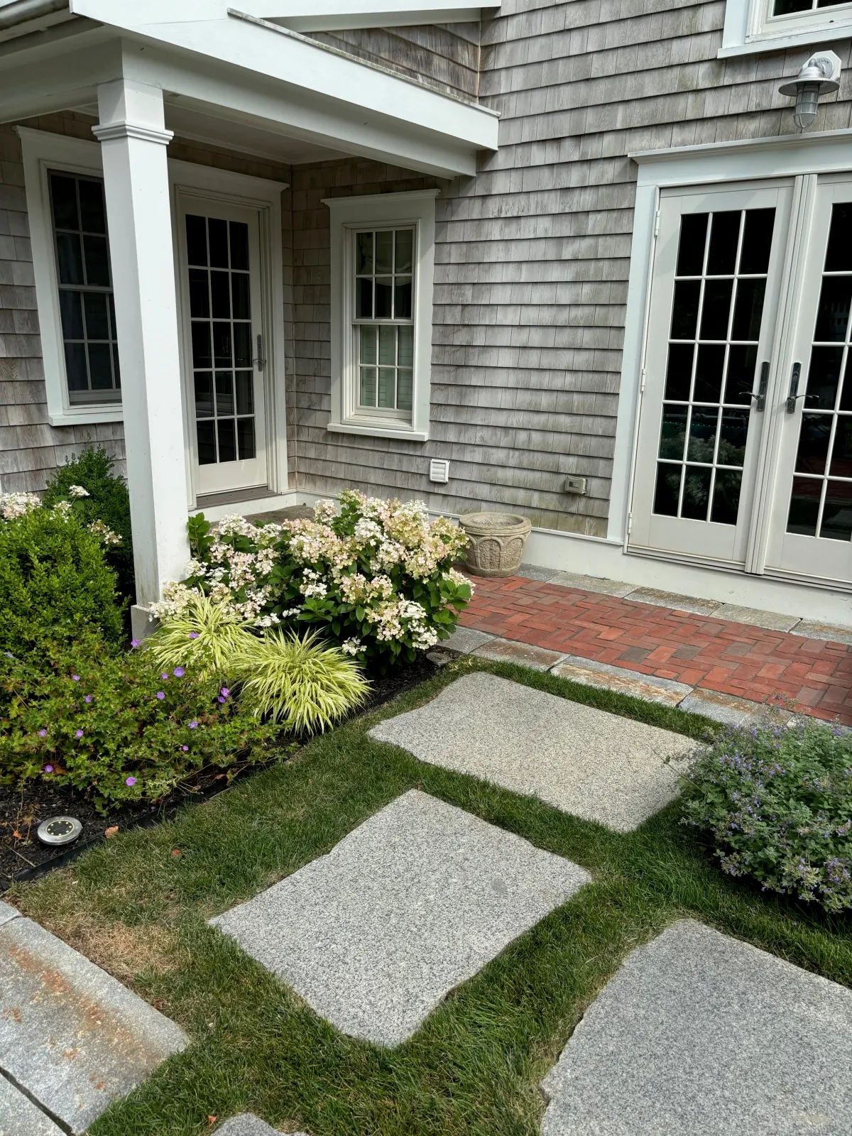 A historic New England home gets a total exterior makeover through clever landscape design that suits the period of the home using reclaimed granite and Boston City Hall brick.
