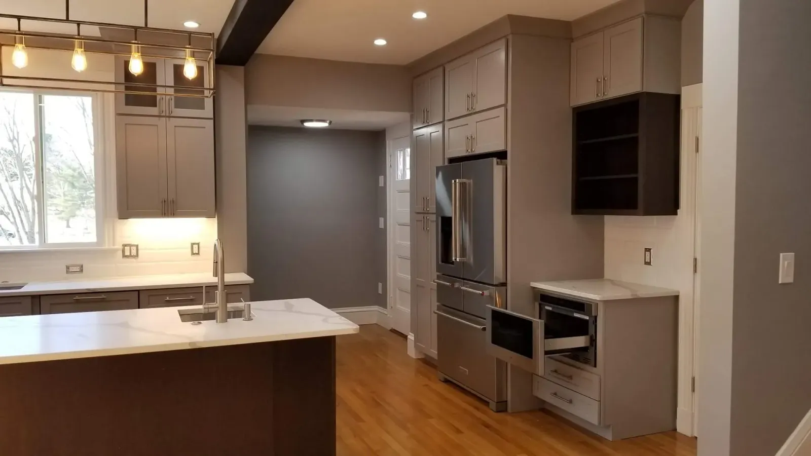 A kitchen with stainless steel appliances and gray cabinets.