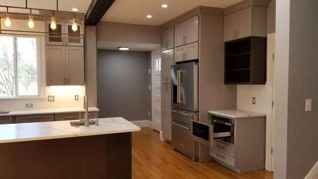 A kitchen with stainless steel appliances and gray cabinets.