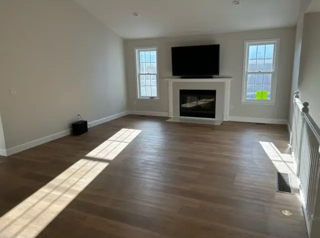 An empty living room with a fireplace and a flat screen tv.