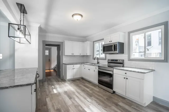 A kitchen with white cabinets , stainless steel appliances , and hardwood floors.