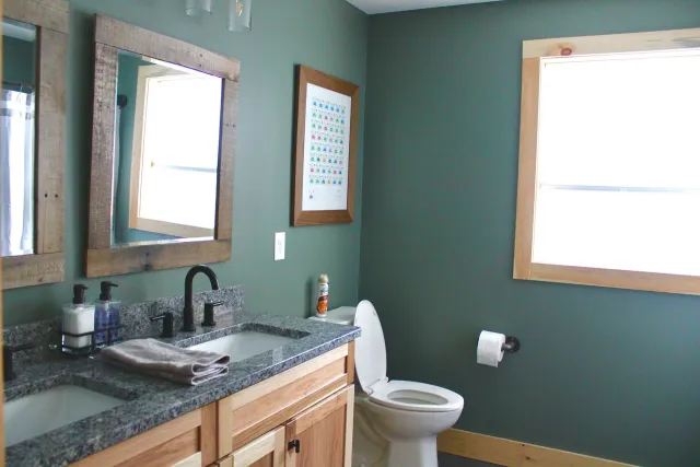 A bathroom with a toilet a sink and two mirrors