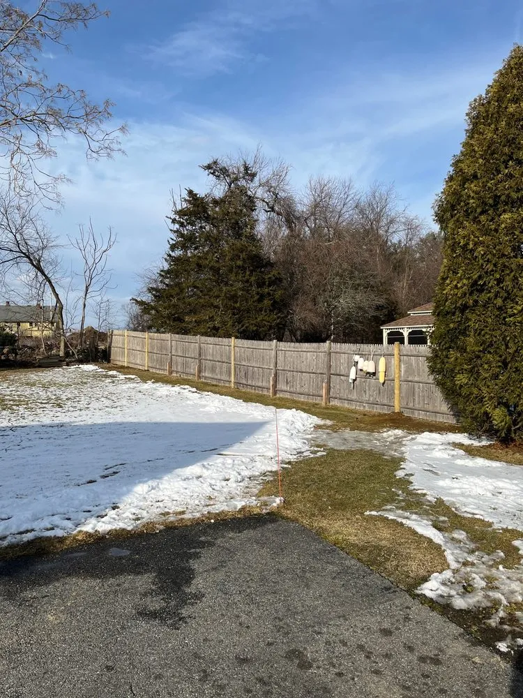 Weathered stockade fence with newly set replacement post