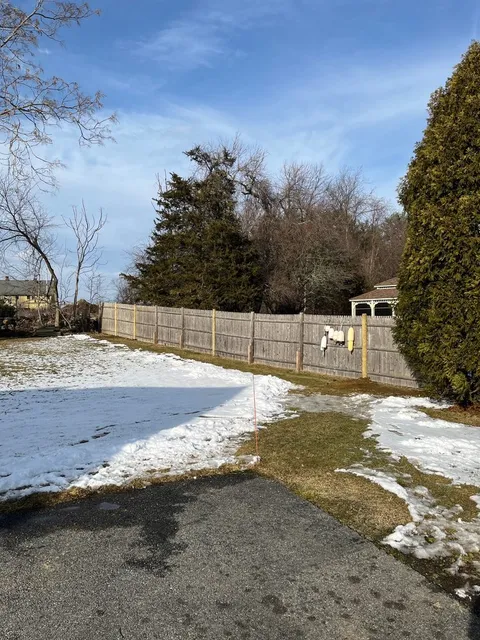 Weathered stockade fence with newly set replacement post