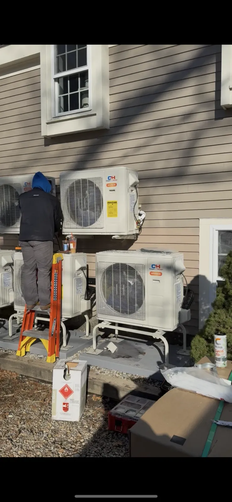 HVAC technician installing dual mini-split condenser units on home exterior