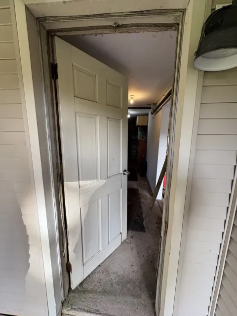 Before replacement: old exterior door open with worn framing visible around the doorway