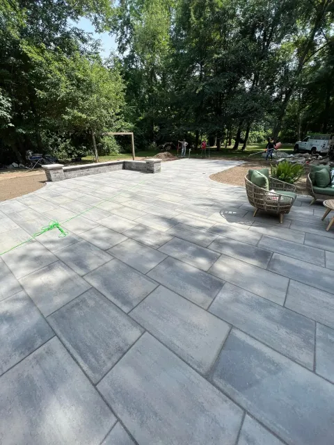 a large patio with chairs and a fire pit surrounded by trees .