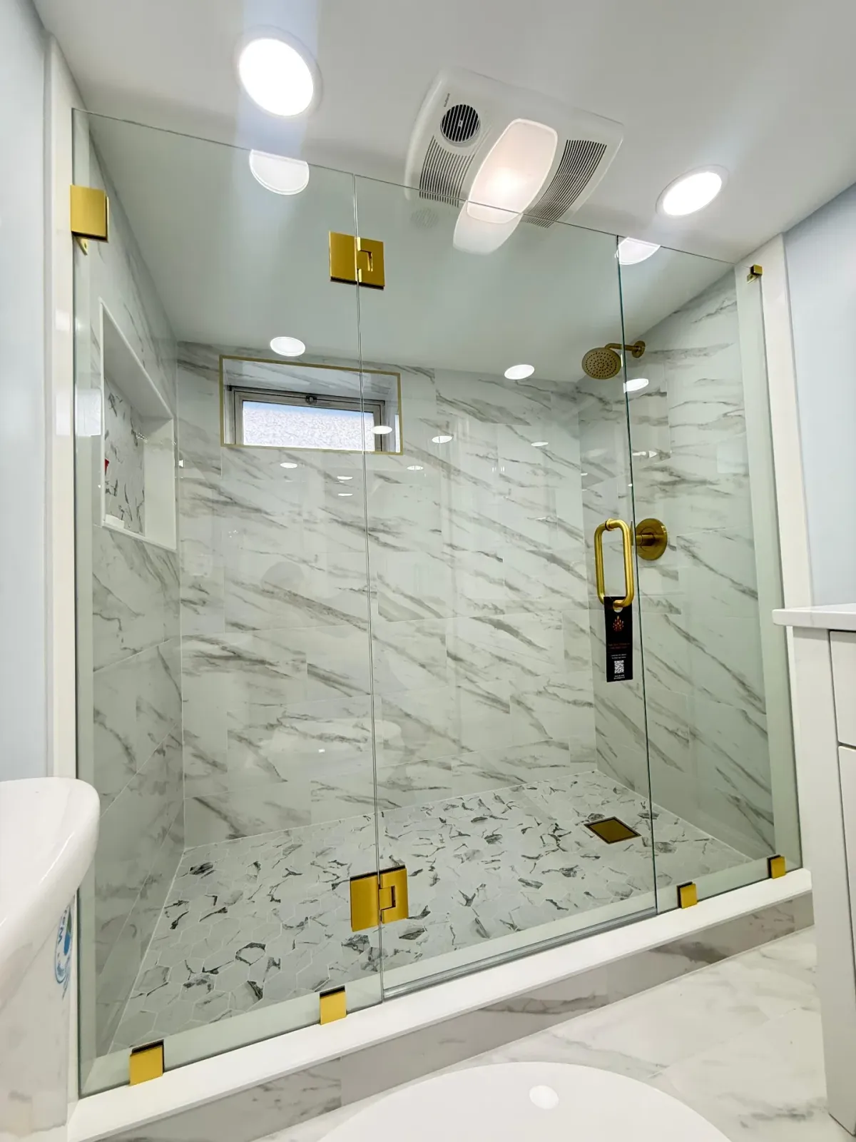 Marble frameless shower with gold fixtures