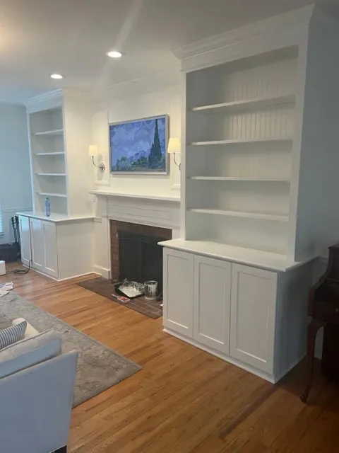 A living room with a fireplace , shelves , cabinets and a flat screen tv.