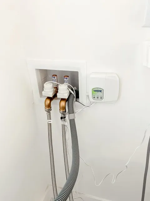 A close up of a washer and dryer hose attached to a wall.