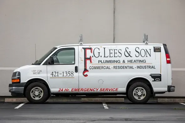 White plumbing service van with “F.G. Lees & Son” lettering parked on a street.