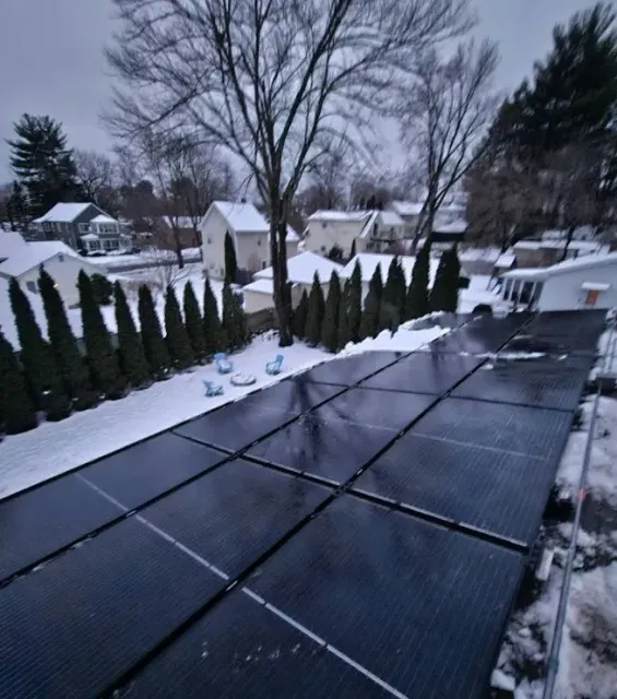 A row of solar panels on a roof in the snow