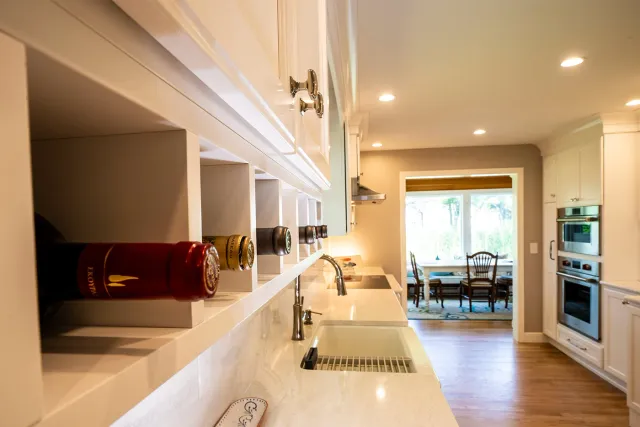 Built-in wine storage and white cabinetry in a bright Seacoast, NH kitchen renovation by Oxland Builders