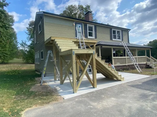A wooden deck is being built on the side of a house.