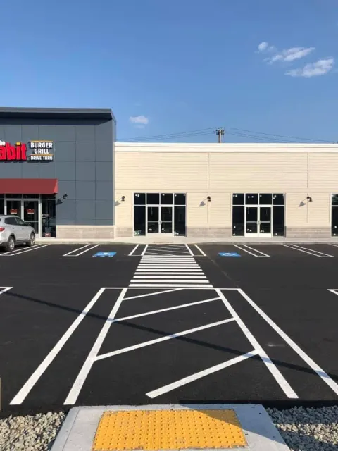 Accessible parking spaces and crosswalk leading to a storefront on a sunny day