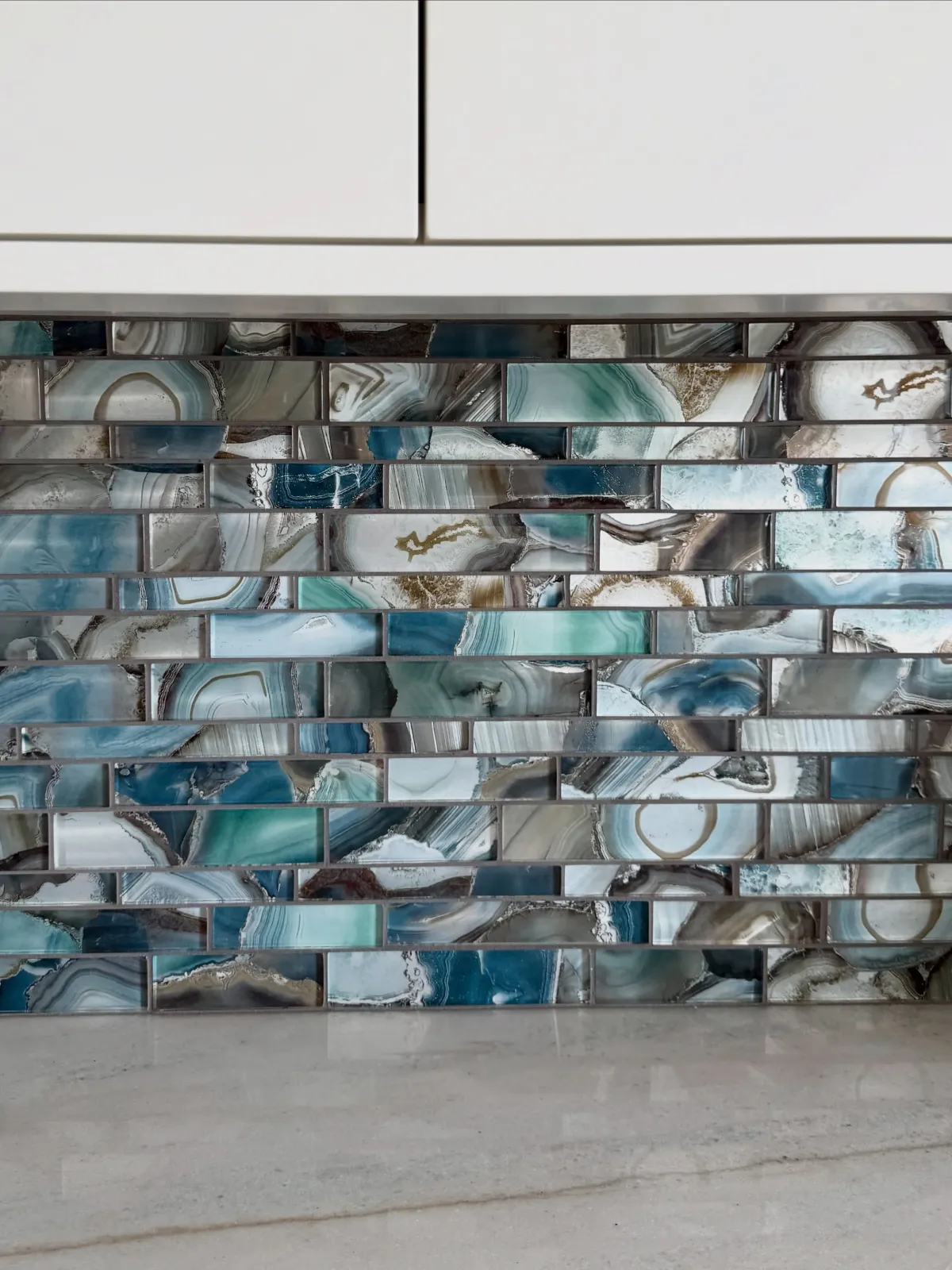 When you live on the ocean, your home becomes an extension of the natural beauty just outside your windows. For this new kitchen, our clients selected this @glazziotiles that reflects the ever-changing colors of the sea - iridescent finishes, rich bl