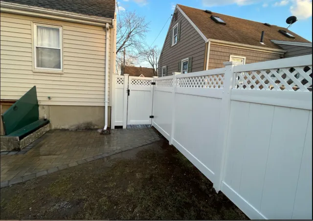 A white fence is in front of a house.