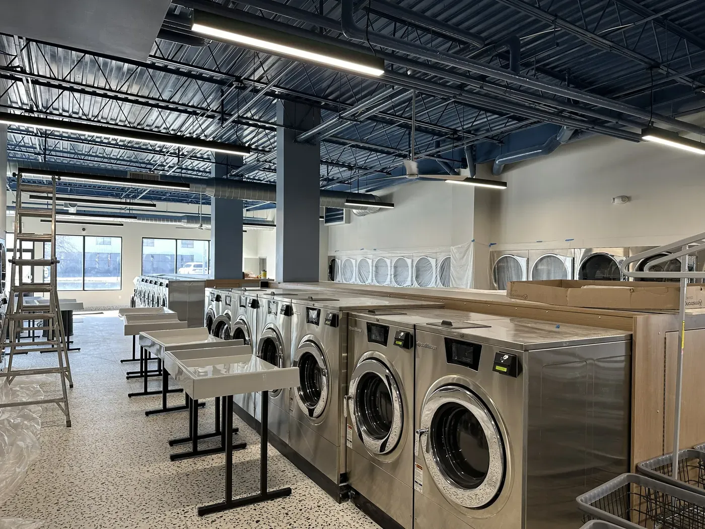 Linear ceiling lighting installed above the machines in a commercial laundromat fit-out