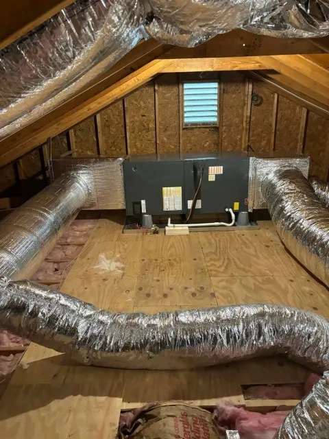 Attic workspace with duct insulation, two monitors, and exposed wood walls and floor