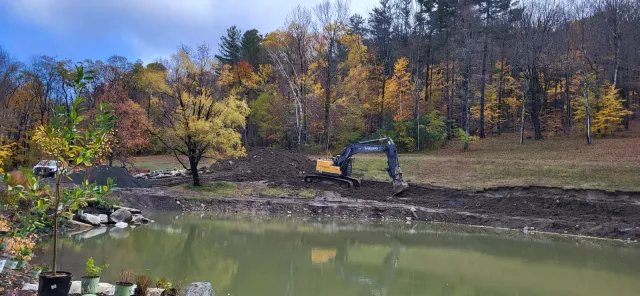Large tracked excavator working along the pond bank during restoration