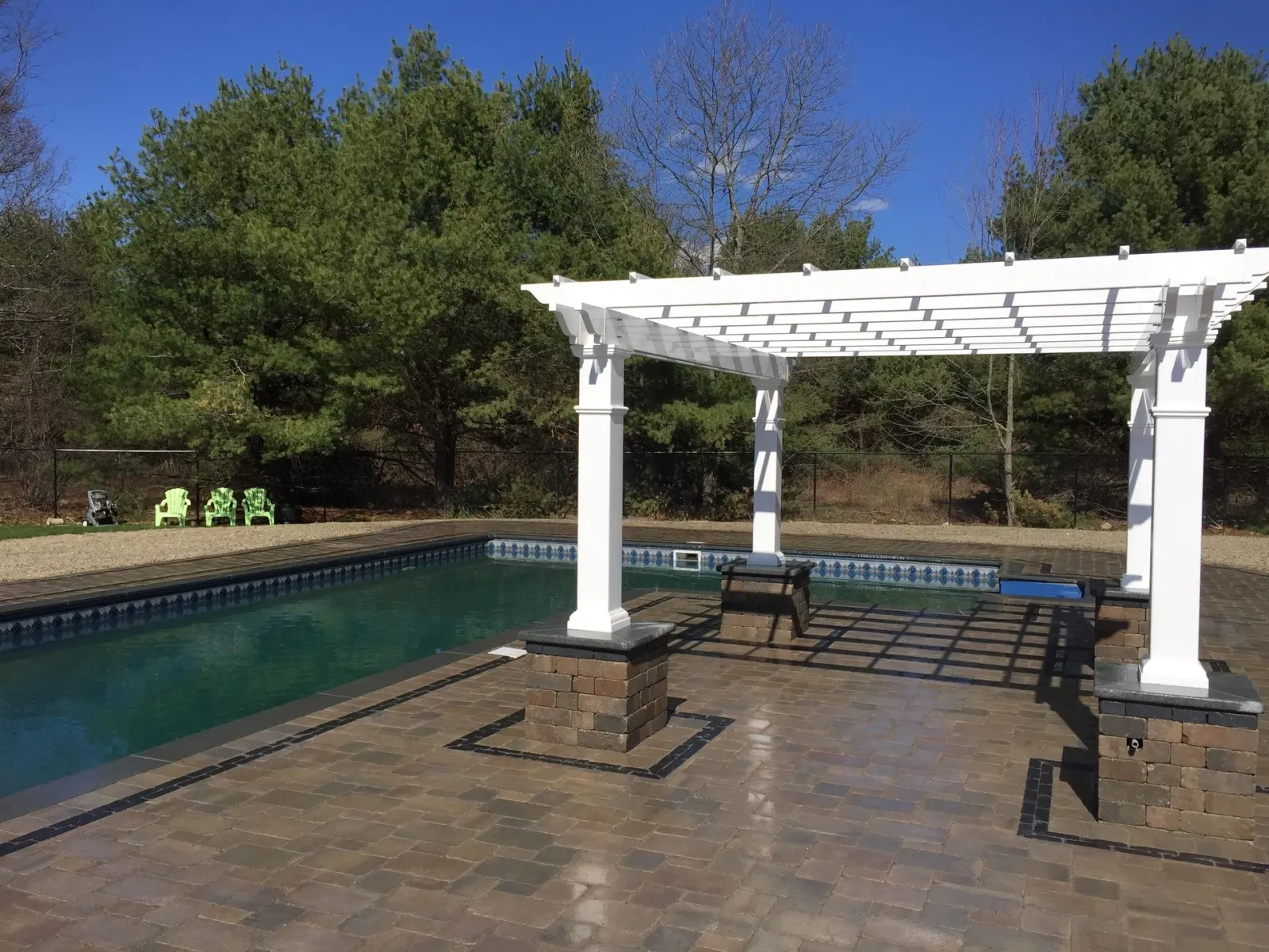 A white pergola is sitting next to a swimming pool.